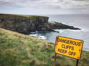 Information sign on rock by sea against sky