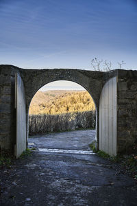 Arch bridge on field against sky