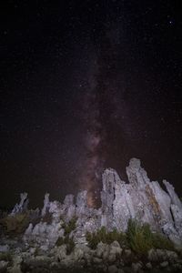 Low angle view of rock formations against star field at night