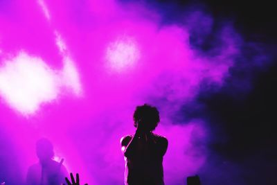 Silhouette man and woman standing against pink sky