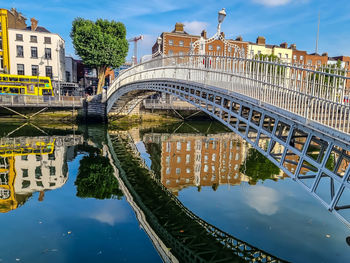 Bridge over river by buildings against sky