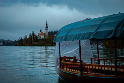 Boat in river by buildings against sky