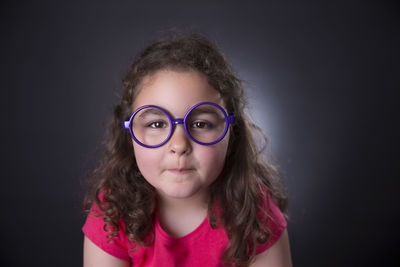 Portrait of girl wearing eyeglasses against black background