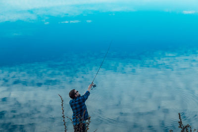 Man fishing in sea against sky