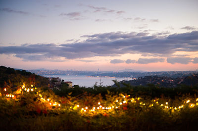 Illuminated cityscape against sky during sunset