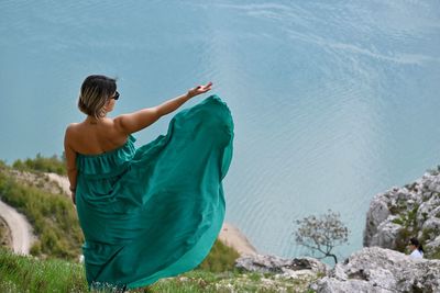 Rear view of woman with arms raised in sea