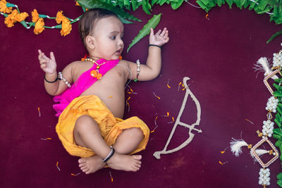 Cute indian boy dresses as lord rama with bow and flowers from top angle