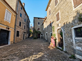 Young woman in pink dress in picturesque old town, village, summer, style, fashion.