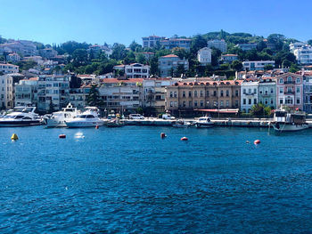 Sailboats in sea against buildings in city