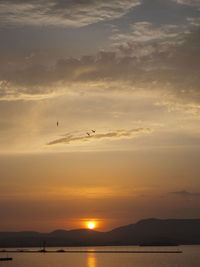 Silhouetted jetty with boats and mountain at dusk