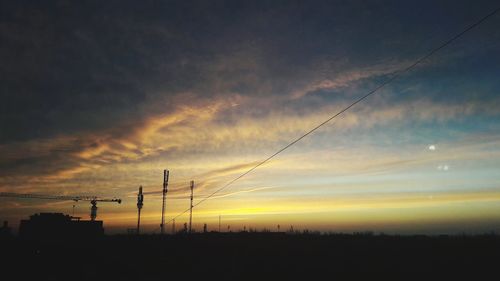 Low angle view of silhouette electricity pylon against sky during sunset