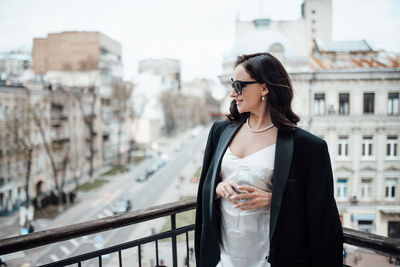 Young woman standing on railing in city