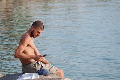 Rear view of shirtless man standing in lake