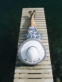 Woman in hat relaxing on pier over sea