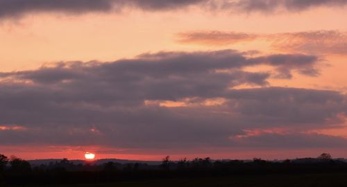 Silhouette landscape against dramatic sky during sunset