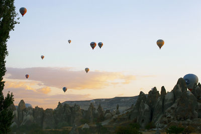 Hot air balloons flying over rocks against sky