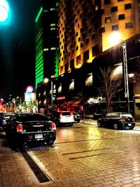 Cars on illuminated street in city at night