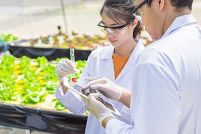 Scientists discussing over digital tablet in greenhouse