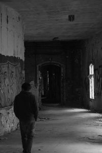 Rear view of man walking in corridor of building