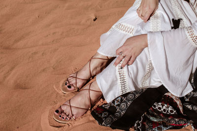 Low section of woman sitting on sand