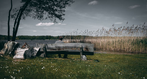 Empty bench on field against sky