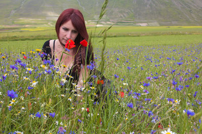 Woman amidst flowering plants on field