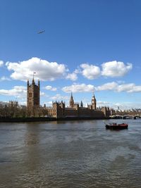 View of city at waterfront against cloudy sky