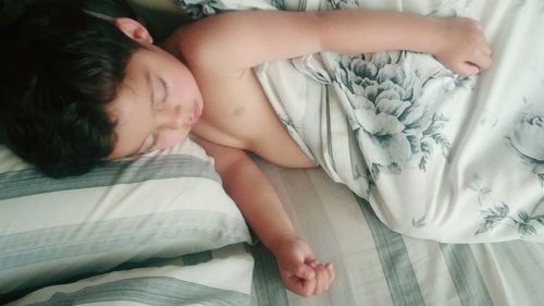 High angle view of cute boy sleeping on bed at home