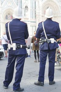 Rear view of police force standing on street