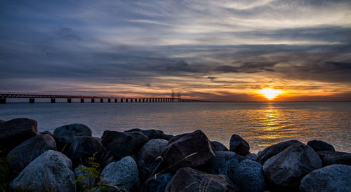 Scenic view of sea against cloudy sky during sunset