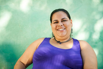 Portrait of smiling young woman against wall