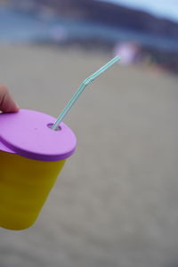 Close-up of hand holding drink at beach