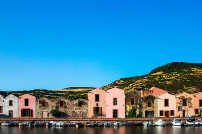 Buildings by canal against clear blue sky
