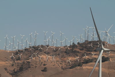 Panoramic view of windmills on desert against clear sky