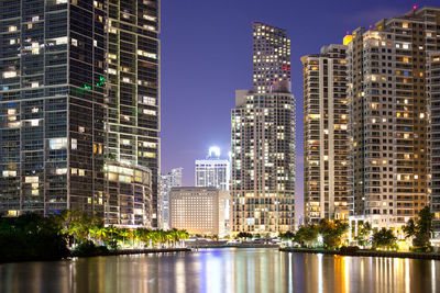 Illuminated buildings in city against sky at night