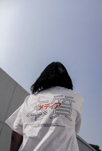 Rear view of man with text against sky