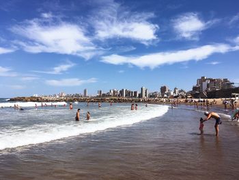 People on beach against sky in city