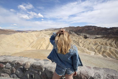 Rear view of woman with hand in hair standing at desert