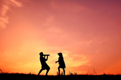 Silhouette of two playful children at sunset