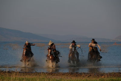 People enjoying in water against clear sky