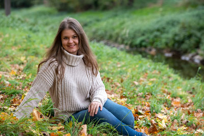 Portrait of a smiling young woman sitting on land