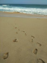 Footprints on sand at beach against sky