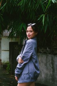 Portrait of young woman standing against plants