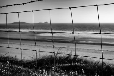 Sea against sky seen through fence