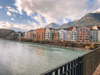 Buildings by river against sky in city