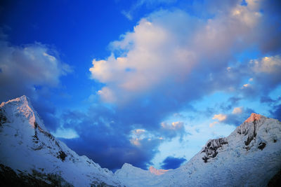 Low angle view of snow covered mountain against blue sky