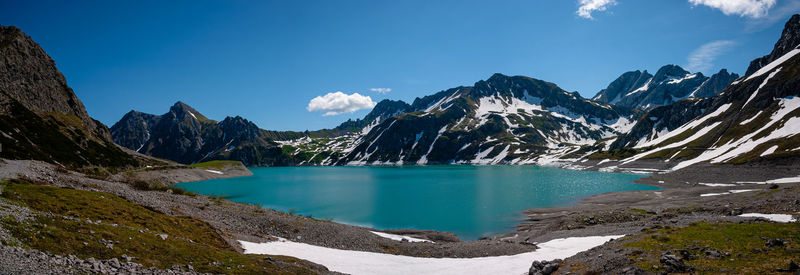Scenic view of lake and snowcapped mountains against blue sky