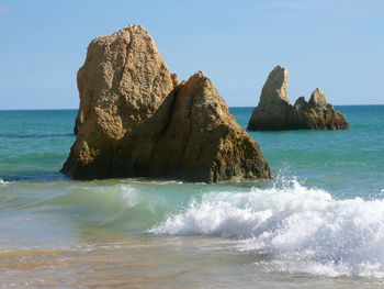 Scenic view of rocks in sea against clear sky