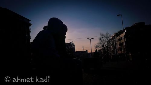 Silhouette man standing by street against sky during sunset