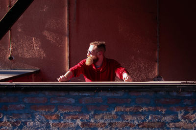 Young man looking away against wall